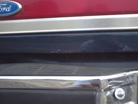 1990 Ford Bronco - Close-up of a red Ford Bronco's rear, showing the emblem and bumper details.