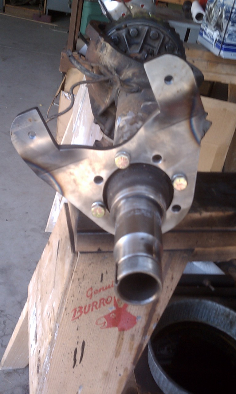 Close-up of a front axle assembly part with bolts and a metal bracket. Text on a box reads 'Genuine BURRO'