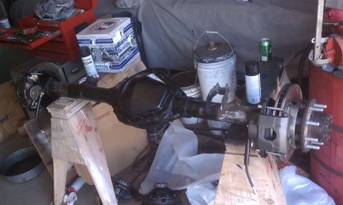 1978 Ford Bronco - A disassembled rear axle assembly sits in a workshop, surrounded by tools and supplies.