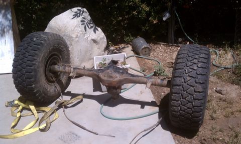 1978 Ford Bronco - A vehicle's rear axle assembly with tires is shown outdoors on a concrete pad.