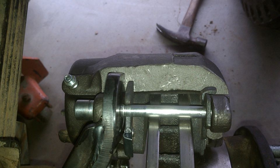 Close-up of a brake caliper assembly with a metal rod passing through it