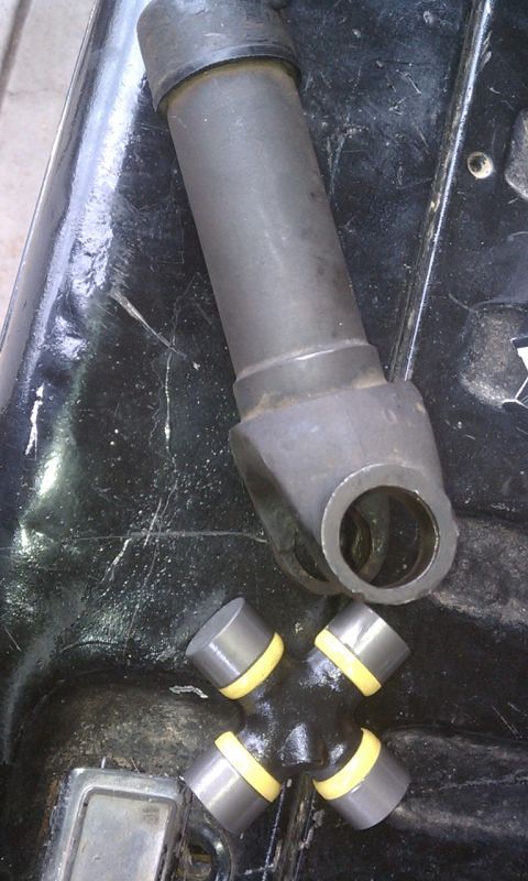 1978 Ford Bronco - A driveshaft yoke and a universal joint are shown on a dark, textured surface.