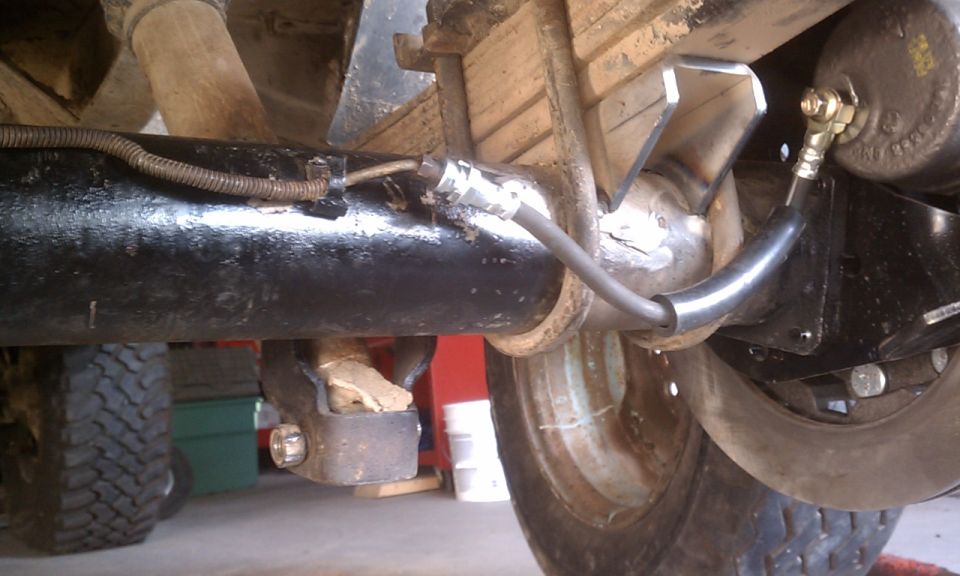 Rear axle assembly with brake lines and suspension components. Some rust visible