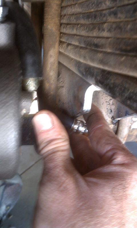 1978 Ford Bronco - Close-up of a hand working on a vehicle's suspension system, focusing on a bolt adjustment.