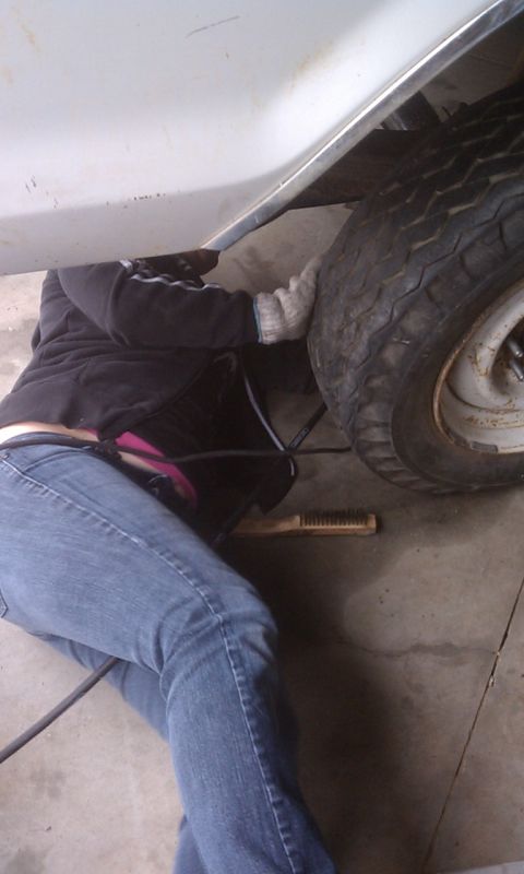 1978 Ford Bronco - A person works on the underside of a vehicle, with a tire visible.