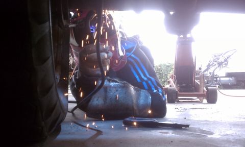 1978 Ford Bronco - Welding sparks illuminate the underside of a vehicle during repairs.