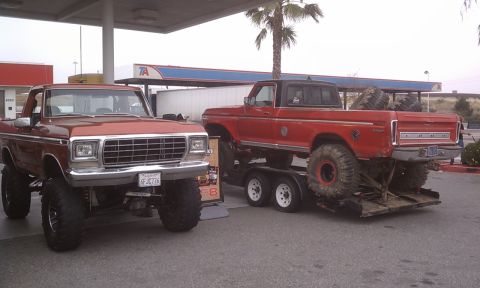 1978 Ford Bronco - A lifted brown 1978 Ford Bronco is parked next to a red Ford truck on a trailer at a gas station.