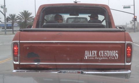 1978 Ford Bronco - This pickup truck has a custom decal on the tailgate and is driving on a street with other vehicles.