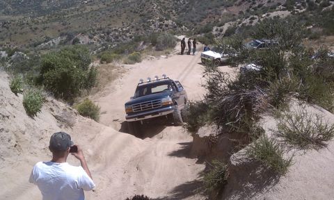 1978 Ford Bronco - A Ford Bronco navigates a steep, sandy off-road trail with other vehicles and spectators present.