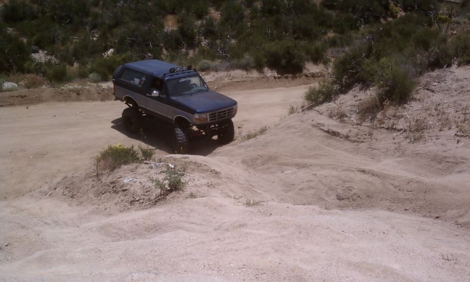 Blue and silver lifted SUV driving on a dirt path