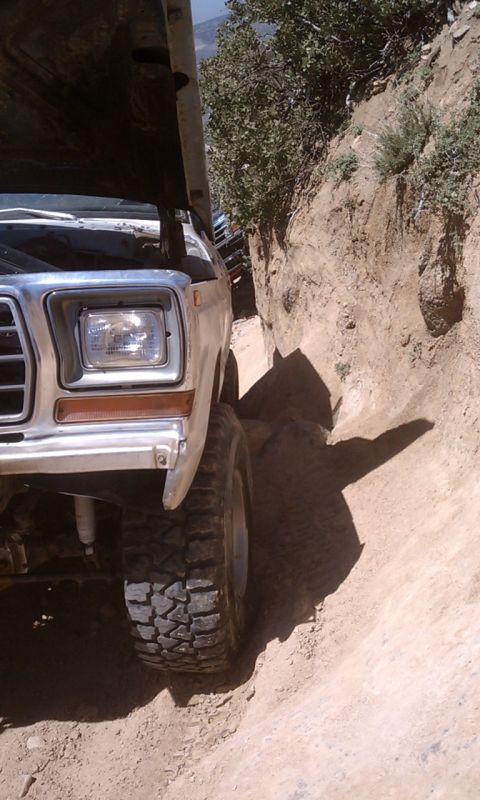 1978 Ford Bronco - This 1978 Ford Bronco navigates a tight, off-road trail with its hood up, revealing the engine bay, partially open.