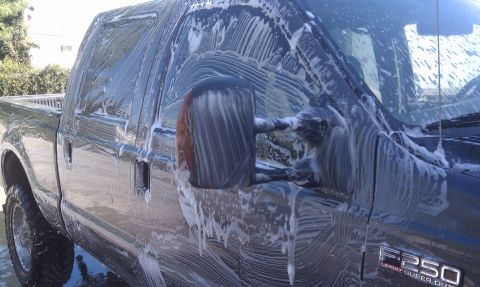 1978 Ford Bronco - Dark blue Ford F-250 Lariat Super Duty crew cab covered in soap suds during a wash, shot from the side showing the fender badge, black tow…