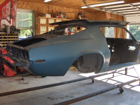 1972 Chevrolet Camaro - The rear section of a blue 1970s muscle car body is shown on a stand in a garage, undergoing restoration.