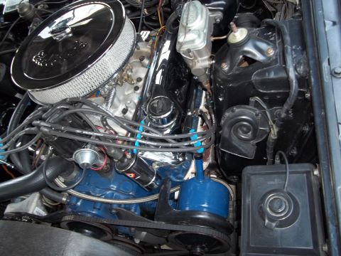 1970 Ford Ranchero - Close-up view of a vehicle's engine bay, a chrome air cleaner and a bright blue fluid reservoir.