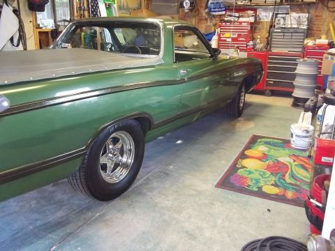 1970 Ford Ranchero - A green 1970 Ford Ranchero is parked inside a garage, showing its side profile and a covered bed.