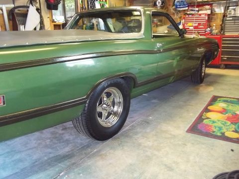 1970 Ford Ranchero - A green 1970 Ford Ranchero is shown from the side in a garage setting, equipped with a tonneau cover and aftermarket wheels.