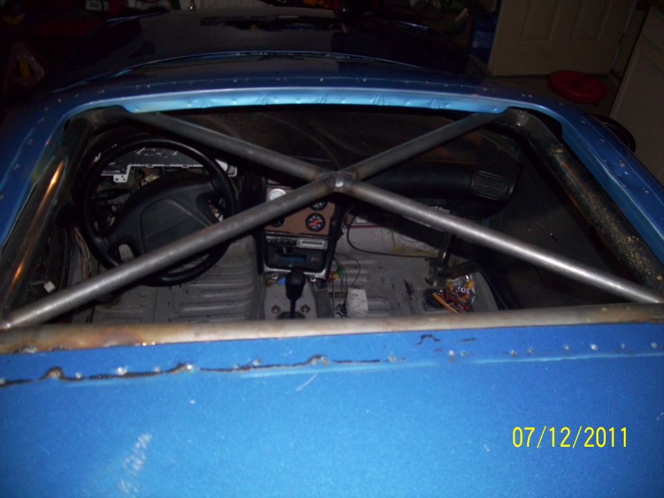 1995 Ford Probe interior with roll cage, aftermarket steering wheel, and manual shifter