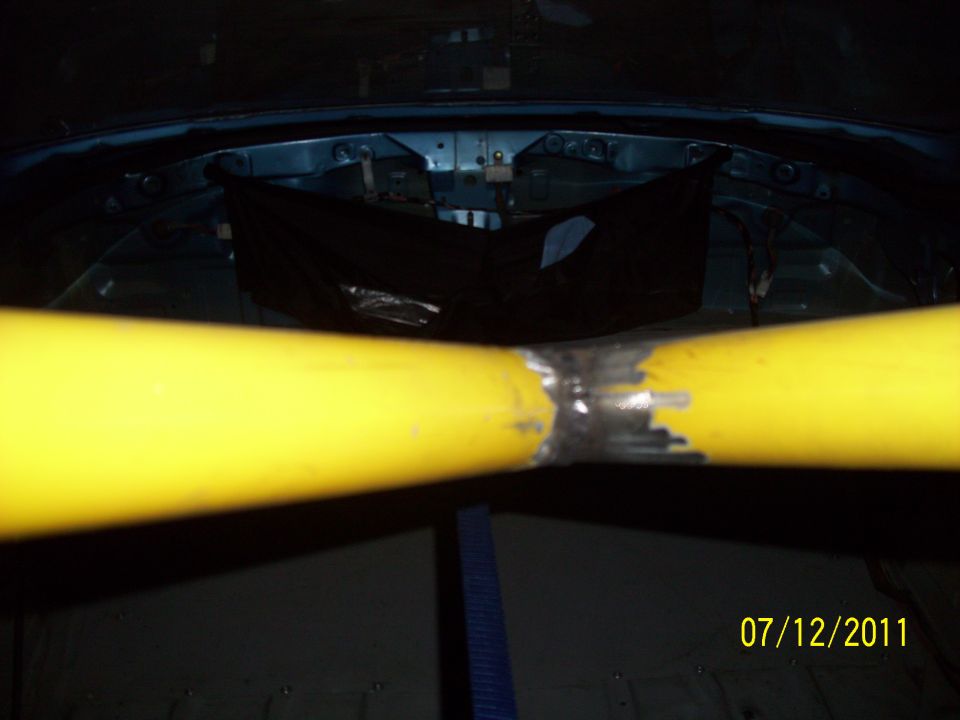 Yellow roll cage bars welded together inside a dark interior