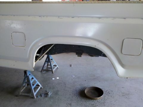 1995 Ford Bronco - The rear quarter panel and wheel well of a white truck are visible, supported by jack stands.