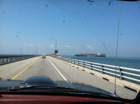 1995 Ford Bronco - View from a vehicle driving on a bridge towards a large cargo ship on the ocean.