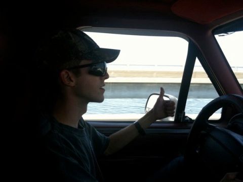 1995 Ford Bronco - A driver gives a thumbs up while on the road, with water visible outside the window.