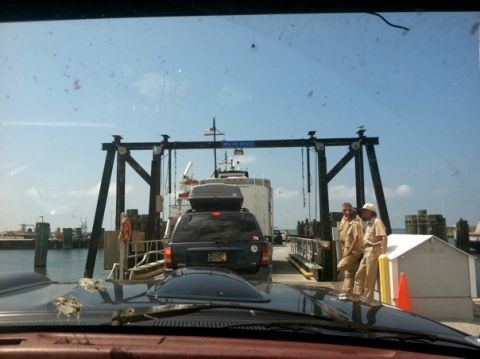 1995 Ford Bronco - A black Jeep Cherokee is parked on a ferry with a cargo box on its roof, viewed from the rear.