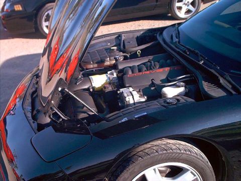 2000 Ford Crown Victoria - Close-up of a black Corvette's engine bay, with the word "CORVETTE" visible on the engine cover.