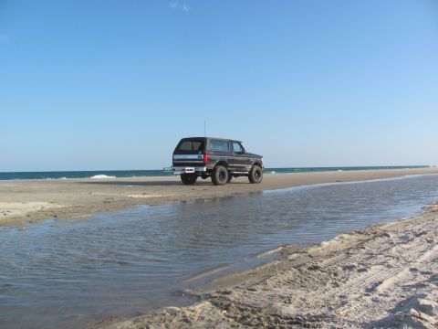 1995 Ford Bronco - This 1995 Ford Bronco is parked on the beach with the ocean in the background.