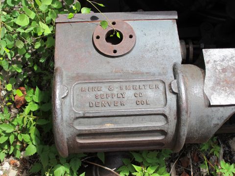 1994 Ford Bronco - A weathered cast iron component, likely from industrial machinery, rests outdoors amidst green foliage.