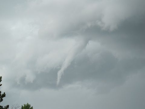 1994 Ford Bronco - Tornado funnel cloud forming in stormy grey clouds, with trees visible at the bottom left.