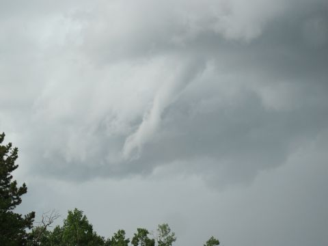 1994 Ford Bronco - A dramatic sky with swirling storm clouds above a line of trees.