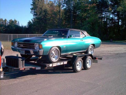 2000 Ford Crown Victoria - A teal convertible muscle car is transported on a trailer.