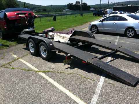 1955 Chevrolet Bel Air - A car trailer is positioned next to a red SUV, with a person loading items into the SUV.