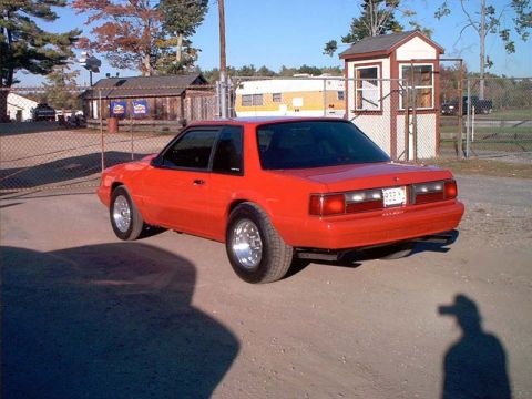 2000 Ford Crown Victoria - Red coupe with aftermarket wheels and custom exhaust parked on a dirt lot.