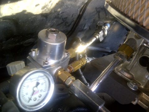 1994 Ford F-150 - A close-up view of a fuel pressure regulator and gauge assembly, with associated plumbing and an air filter housing visible.