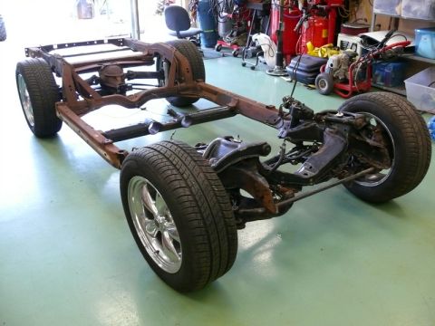 1976 Chevrolet Corvette - The frame and suspension of a car are shown, with visible rust and chrome wheels.
