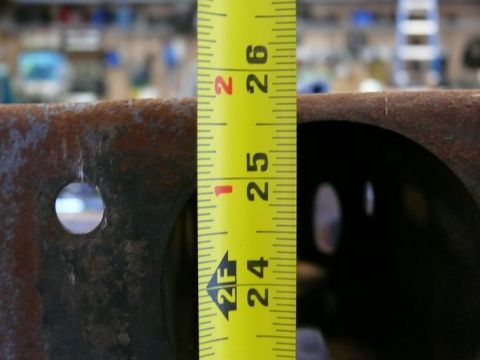 1976 Chevrolet Corvette - A yellow measuring tape is placed against a rusty metal object, indicating a measurement of approximately 25.5 inches.