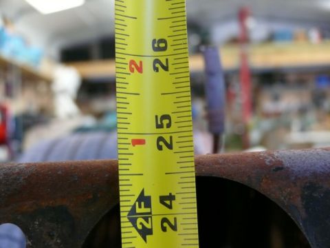 1976 Chevrolet Corvette - A tape measure is used to measure a piece of rusty metal in a workshop.