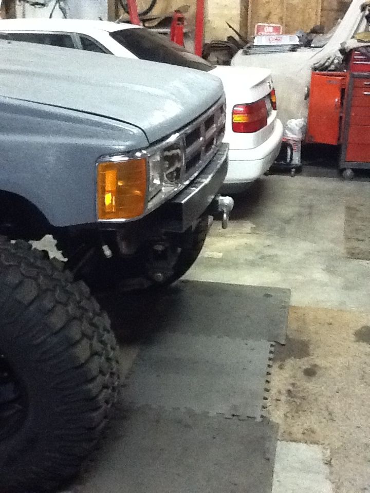 Gray truck front end with amber turn signals, chrome grille, and aftermarket bumper