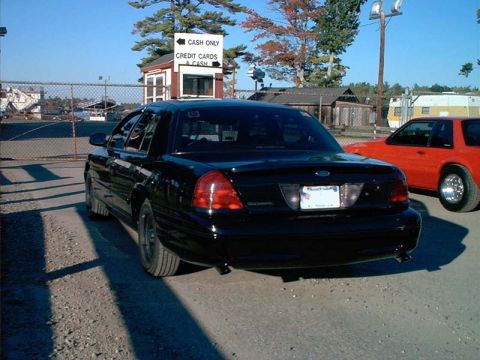 2000 Ford Crown Victoria - Rear view of a black 2000 Ford Crown Victoria, parked at a dragway with a red car visible to the right.