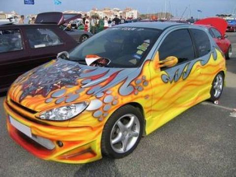 1991 Ford LTD Crown Victoria - Customized Peugeot 206 hatchback with flame graphics and body kit parked outdoors.