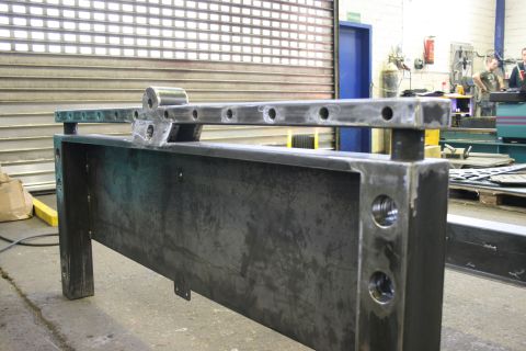 1973 Ford Ranchero - A custom metal frame is shown in a workshop setting, with tools and machinery visible in the background.