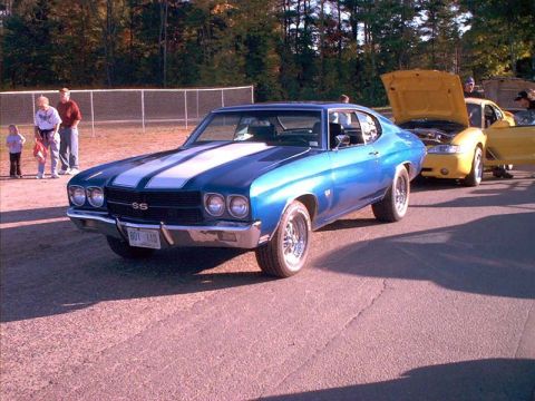 2000 Ford Crown Victoria - A blue 1970 Chevelle SS and a yellow car are parked at an outdoor event, with people in the background.