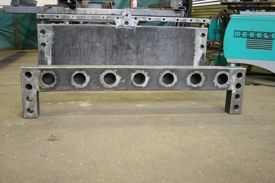 Fabricated steel component with multiple circular holes and vertical mounting brackets
