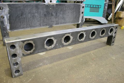 1973 Ford Ranchero - A fabricated metal frame with numerous circular holes is shown in a workshop setting.