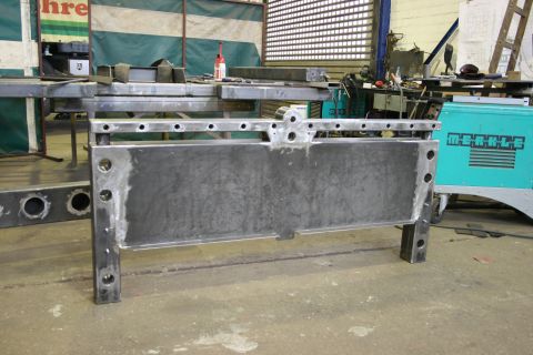 1973 Ford Ranchero - A metal frame sits in a workshop, with welding equipment visible in the background.