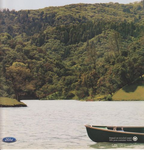 1996 Ford Bronco - A dark green wooden rowboat floats on a calm lake in the foreground, with forested hillsides rising in the background. This appears to be a…
