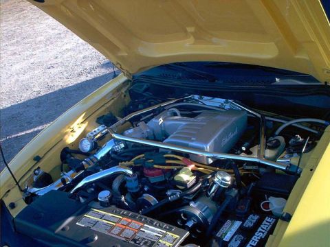 2000 Ford Crown Victoria - Close-up of a yellow Ford Mustang's engine bay, showing the intake manifold and various engine components.
