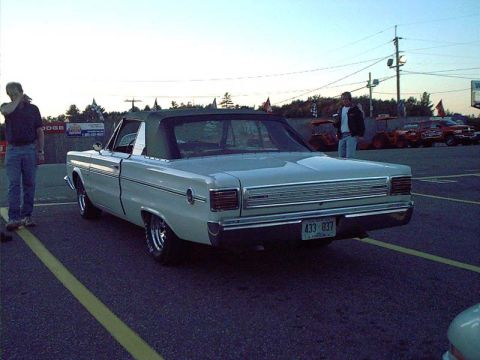 2000 Ford Crown Victoria - A classic convertible is parked at an outdoor event with other vehicles and people in the background.