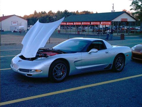 2000 Ford Crown Victoria - Silver Chevrolet Corvette with its hood open, parked at a drag strip with another car visible.